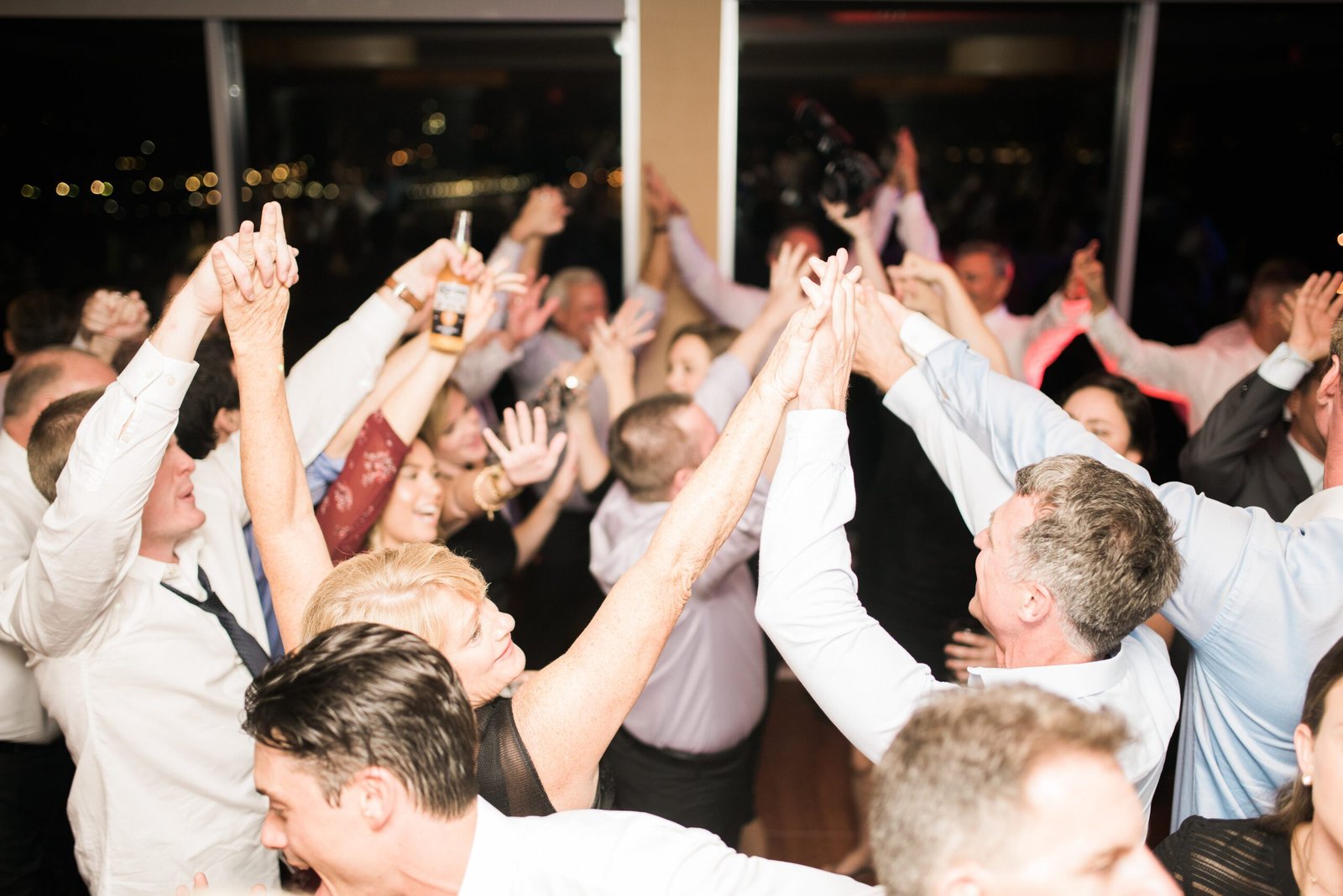 [No Logo] Enthusiastic wedding guests raising their arms on a packed dancefloor in a Washington DC area wedding.